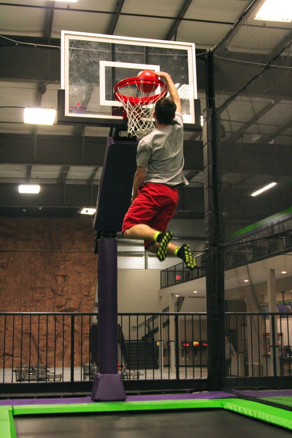 Teen Slam Dunking on Trampoline Basketball Park